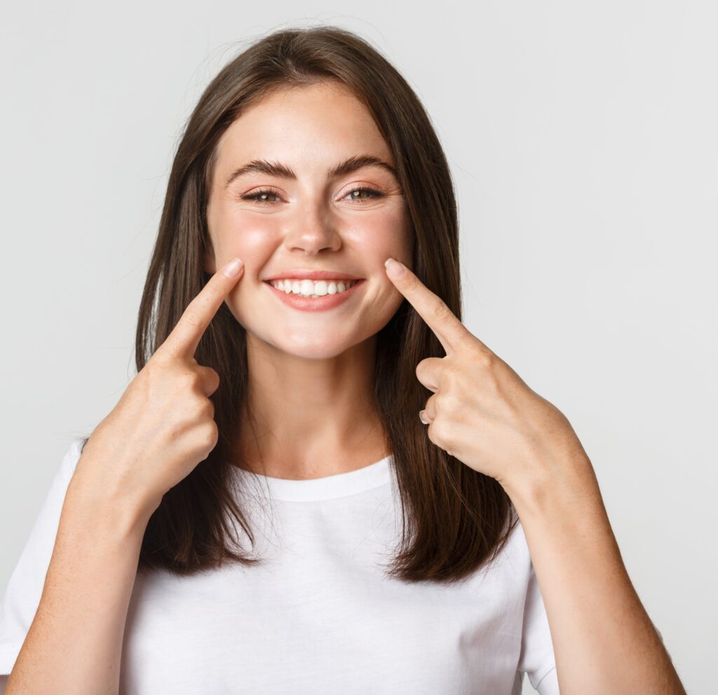 mujer joven mostrando su sonrisa saludable tras un cuidado bucal completo